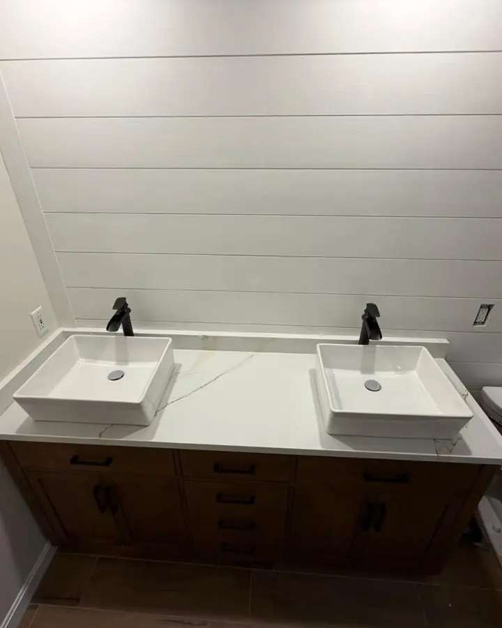 Double vanity with two white vessel sinks and black faucets