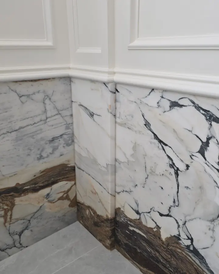 Bookmatched white marble with dark veins running along a bathroom wall