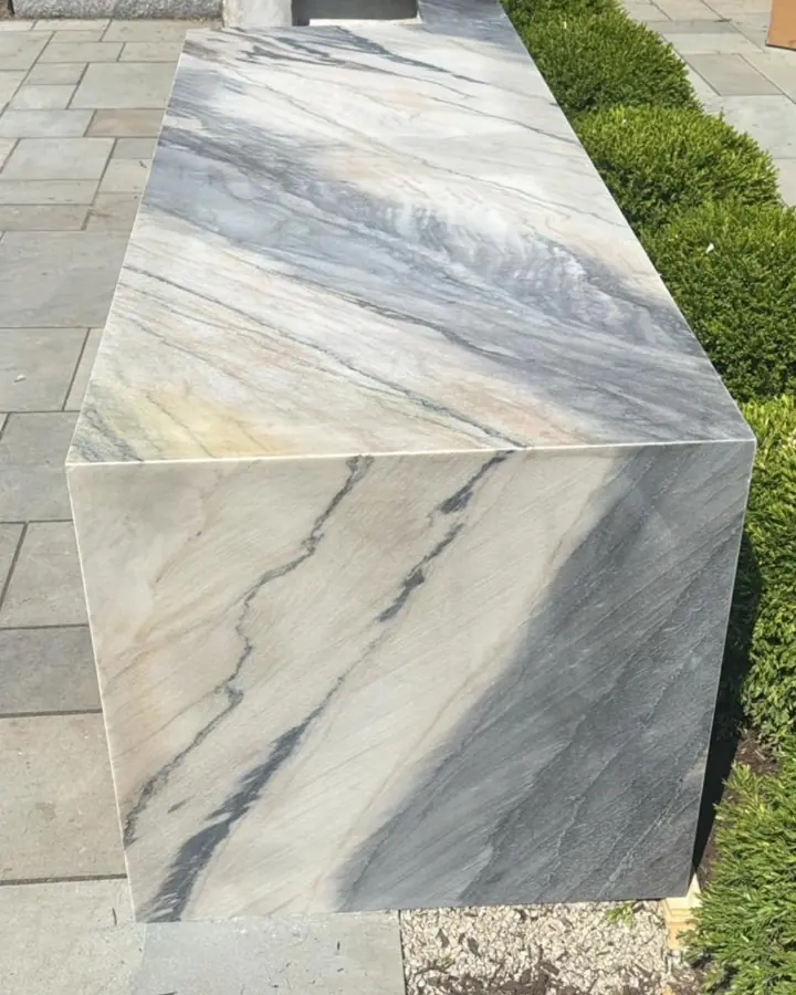 Outdoor kitchen block wrapped in quartzite on a bluestone patio