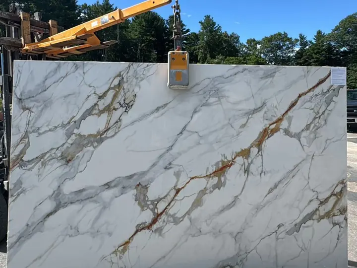 A white slab with gold veins lifted off the truck in the yard
